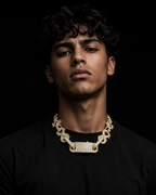 DRIPLORE gold iced-out cuban link chain worn by male model, black tee, cold studio lighting, streetwear