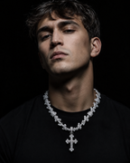 DRIPLORE iced-out cuban chain with baguette cross pendant worn by male model, black tee, cold studio lighting, streetwear